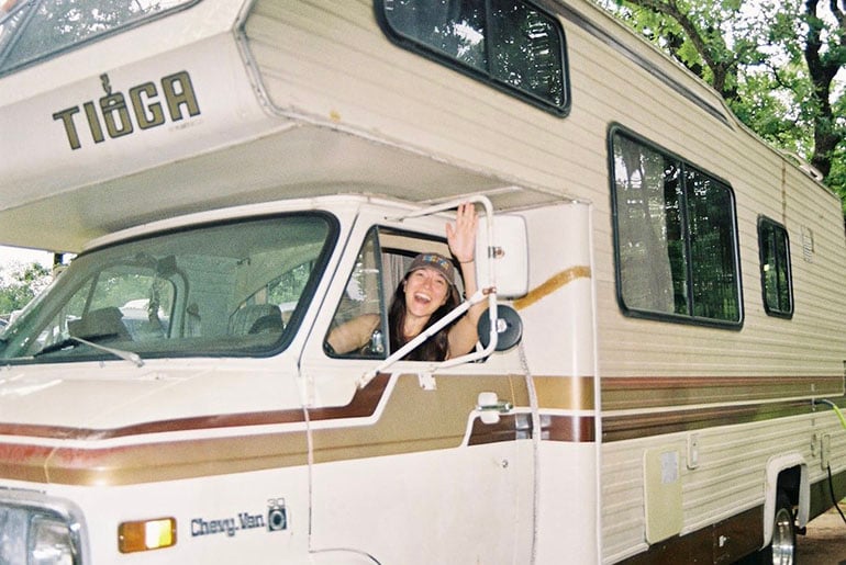 Woman waves out the window of an RV